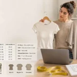 Woman comparing two medium T-shirts beside a women's T-shirt size chart in cm with bust, waist, hip, and shirt length measurements.